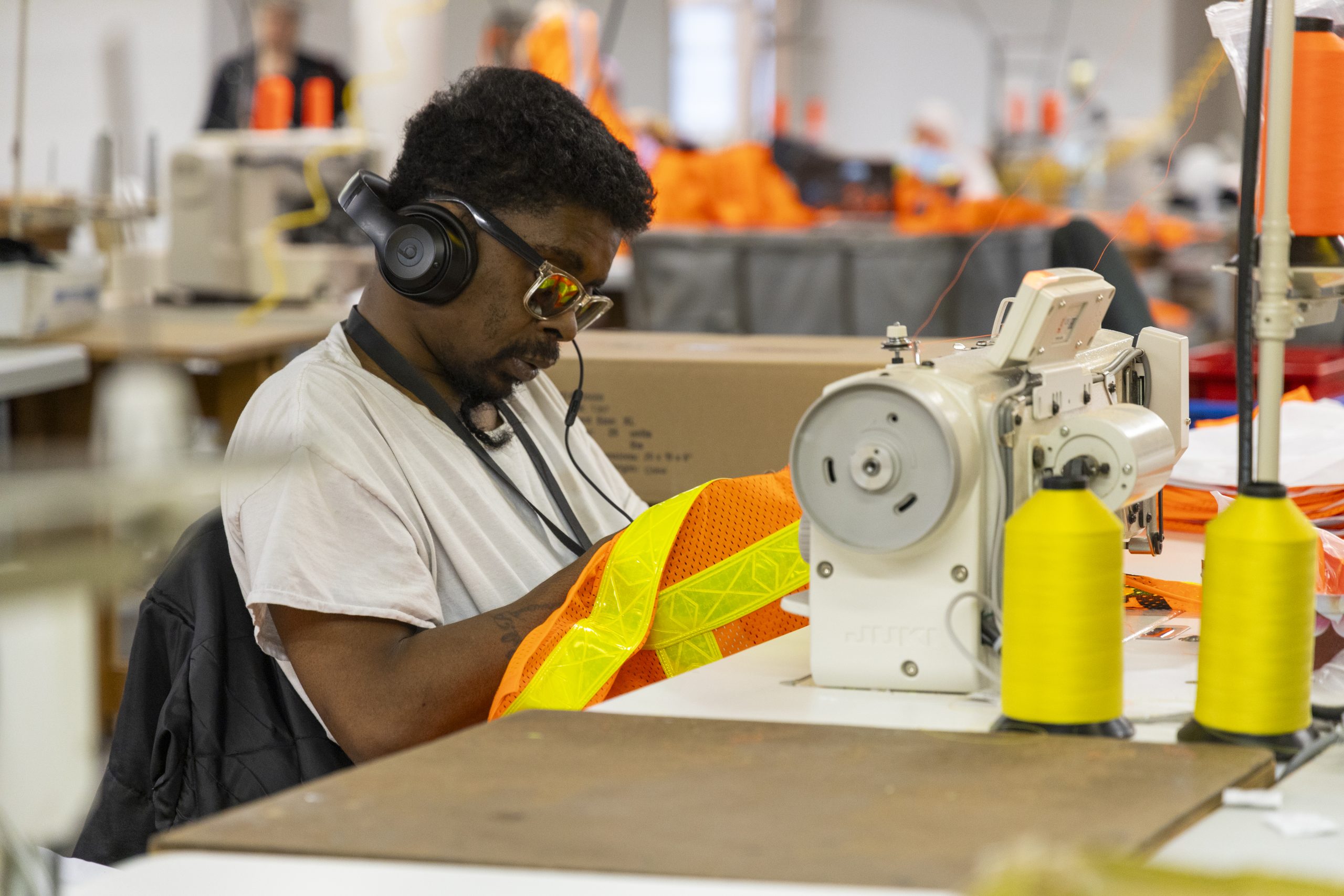 Man sewing MTA vests in manufacturing warehouse