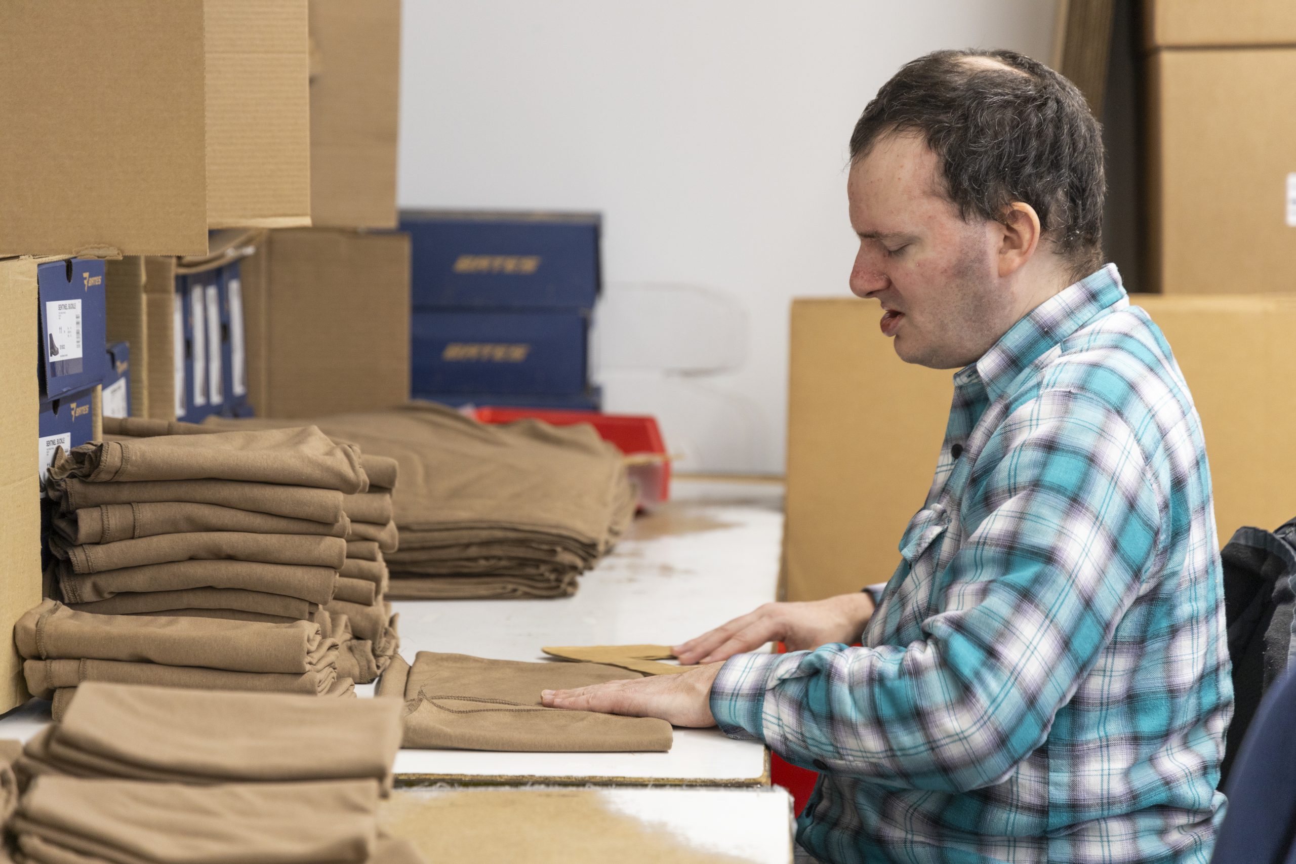 Visually impaired man works in manufacturing warehouse folding fabric