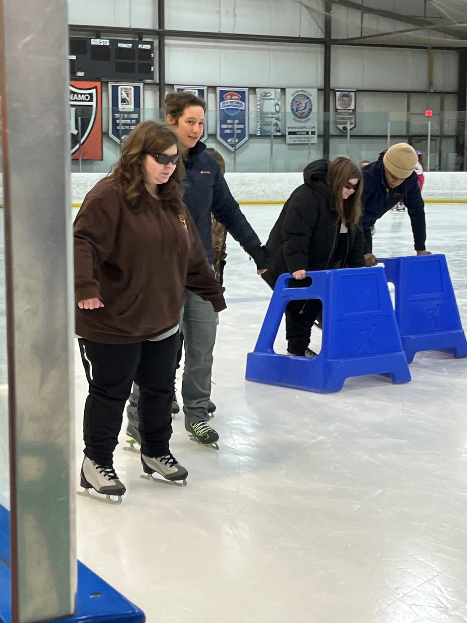 Group of visually impaired people ice skating with guides